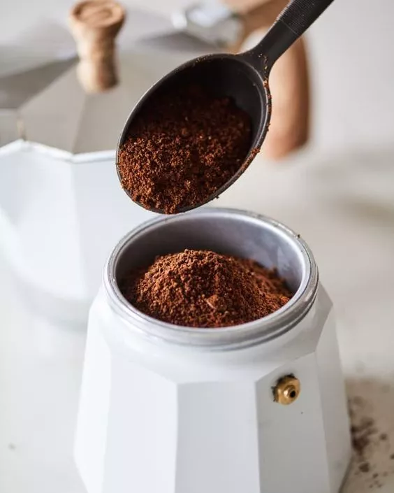 ریختن قهوه آسیاب شده در سبد قهوه